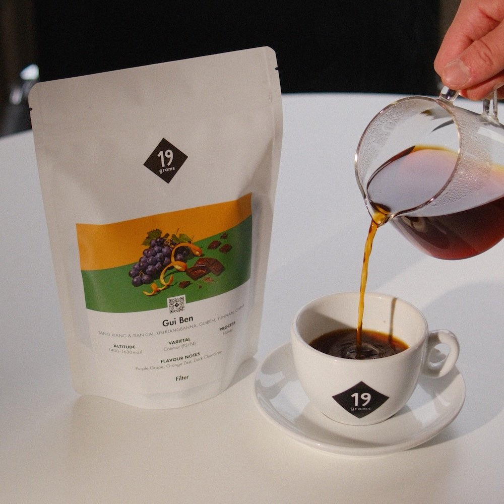 Frisch gebrühter Gui Ben Specialty Coffee wird aus einer Glaskanne in eine 19grams Tasse eingeschenkt