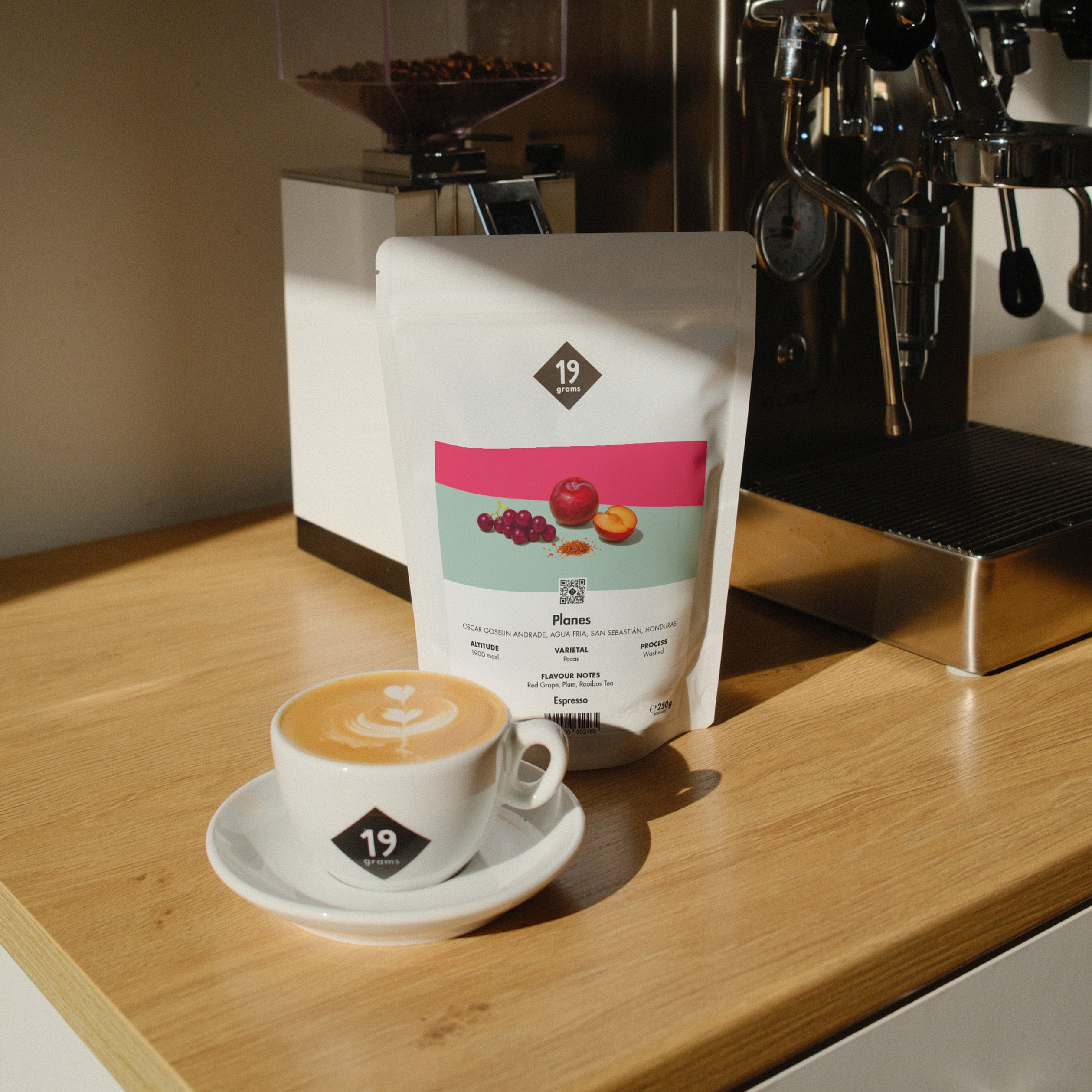 19grams Planes Specialty Coffee Espresso – Kaffeebeutel neben Cappuccino mit Latte Art an der Siebträgermaschine, Single Origin aus Honduras, Kaffeerösterei Berlin