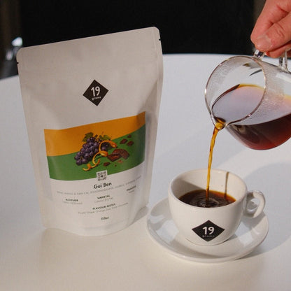 Frisch gebrühter Gui Ben Specialty Coffee wird aus einer Glaskanne in eine 19grams Tasse eingeschenkt