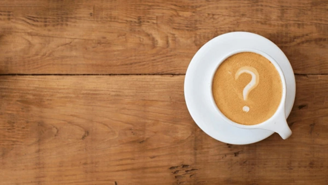 19grams Kaffee-Experten Quiz - 3 Fragen an die Rösterei mit kreativem Fragezeichen-Latte-Art in weißer Porzellantasse auf rustikalem Holztisch