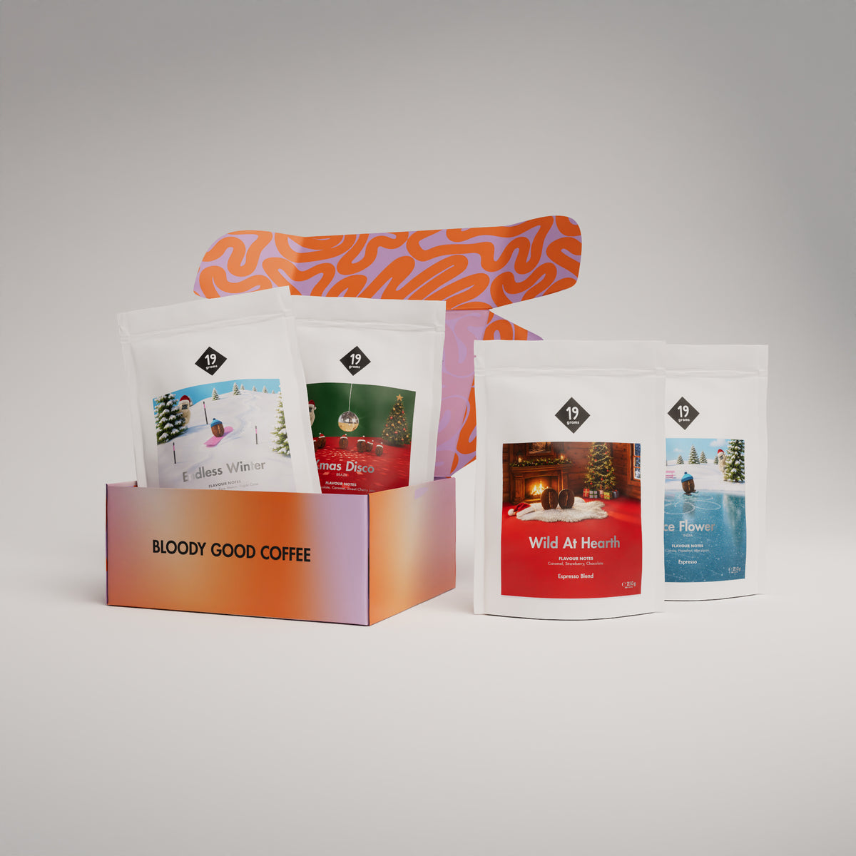 19grams Classic Adventskalender Espresso – Produktmockup mit oranger Geschenkbox „Bloody Good Coffee“ und vier Kaffeebeuteln der Serie (Endless Winter, Xmas Disco, Wild At Hearth, Ice Flower), Kaffeerösterei Berlin