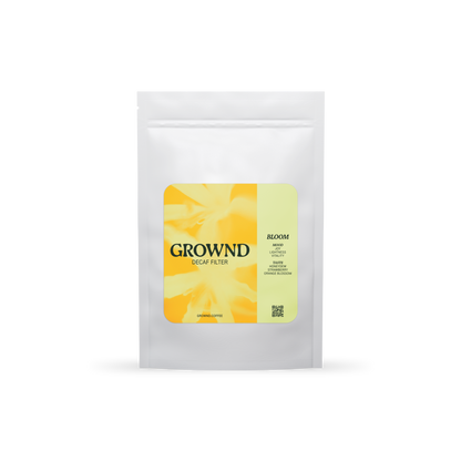 19grams GROWND BLOOM Filter Decaf – Freigestellter weißer Kaffeebeutel mit gelbem Blüten-Label, Geschmacksnoten Honigmelone, Erdbeere und Orangenblüte