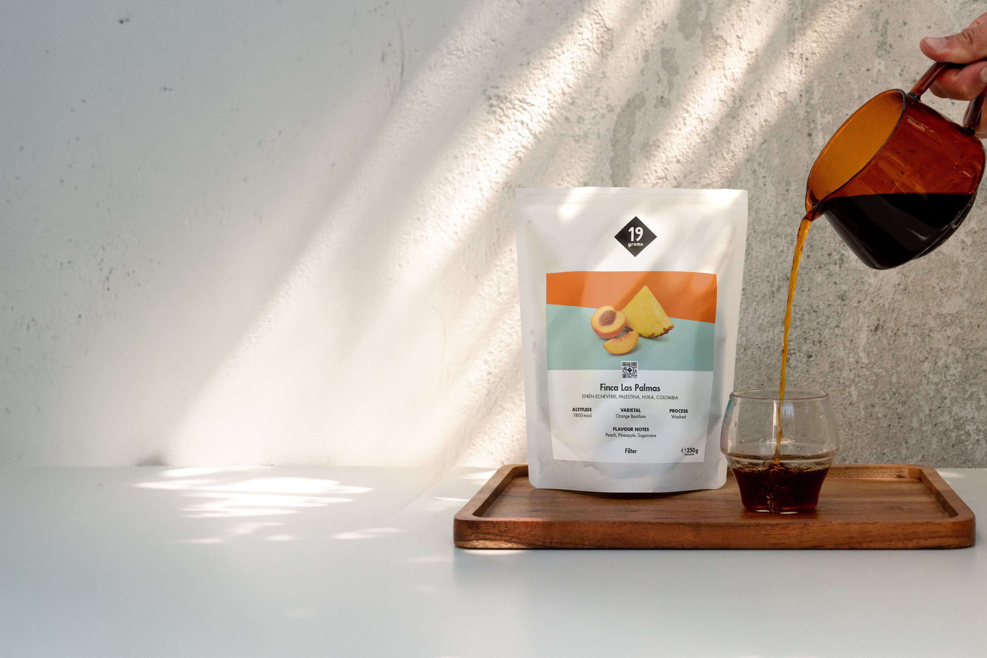 19grams Finca Las Palmas Kolumbien Filterkaffee Bannerbild – Kaffeebeutel mit eingeschenktem Filterkaffee auf Holztablett, Orange Bourbon Washed, Specialty Coffee Rösterei Berlin