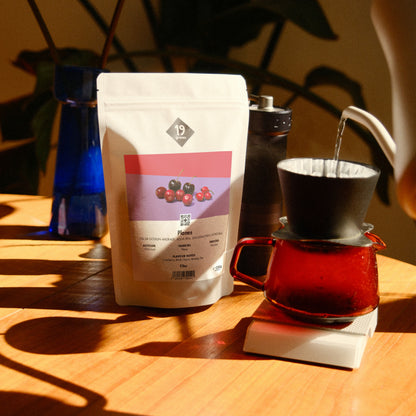 19grams Planes Specialty Coffee Filter – Kaffeebeutel neben Pour-Over-Handaufguss mit Glaskaraffe auf Holztisch im warmen Licht, Single Origin aus Honduras, Kaffeerösterei Berlin
