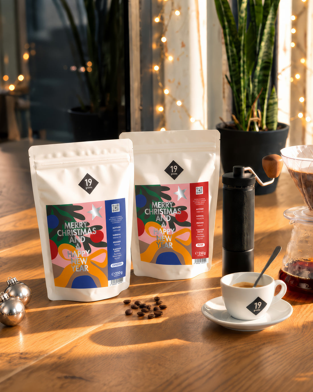 19grams Christmas Coffee Kaffee – 250g – Filter- und Espresso-Beutel auf einem Holztisch mit Handmühle, Glaskaraffe und Espressotasse im warmen Abendlicht