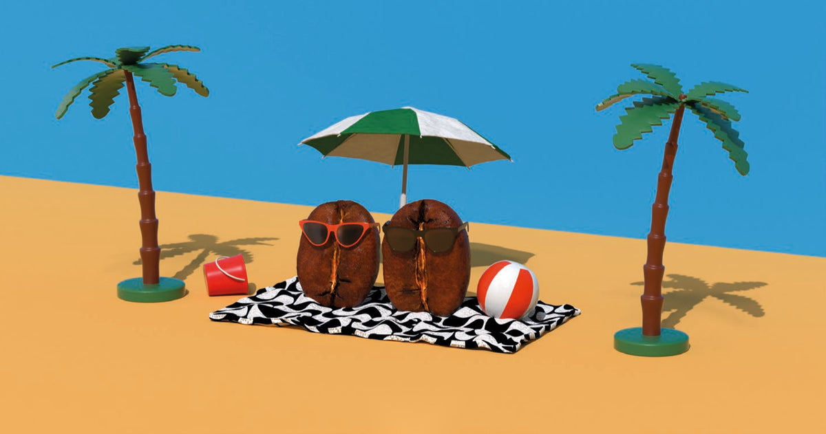 Das Etikett: Zwei Kaffeebohnen mit Sonnenbrillen liegen auf einem schwarz-weiß gemusterten Handtuch am Strand, daneben ein roter Eimer, ein Strandball, ein Sonnenschirm und zwei Palmen.